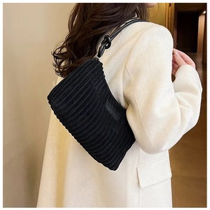 Detail of minimalist black corduroy shoulder bag showing vertical striped texture on faux fur coat