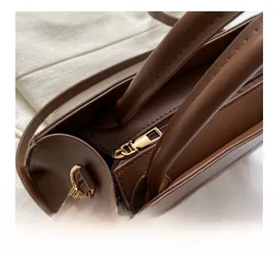 Close-up of smooth gold zipper hardware on a dark brown textured leather tote bag