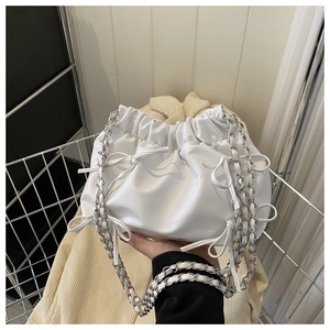 Close-up of pleated white cloud bag with bow detail and silver chain shoulder strap