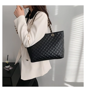 Detail of black quilted chain tote bag worn by a model in a high-quality studio setting