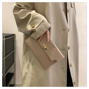 Detail of beige faux crocodile skin texture and gold metal twist lock on chic clutch bag