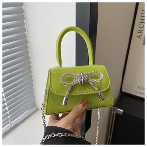 Detail of neon green mini bag featuring a silver rhinestone bow and delicate chain strap