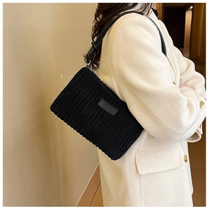 Detailed texture of black corduroy shoulder bag with leather strap and zipper
