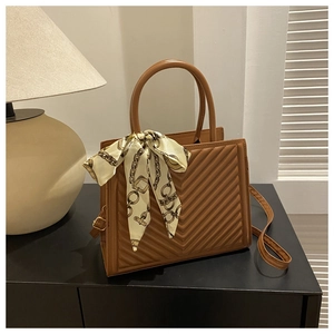 Détail du sac cabas matelassé caramel avec motif en V et foulard décoratif en soie