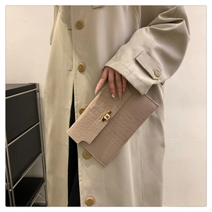 Detail of beige envelope clutch bag with crocodile texture and gold metal twist lock