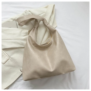 Detail of hobo shoulder bag with knot handle design on white fabric background