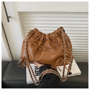 Detail of brown PU leather bucket bag with ribbon bow and silver chain strap