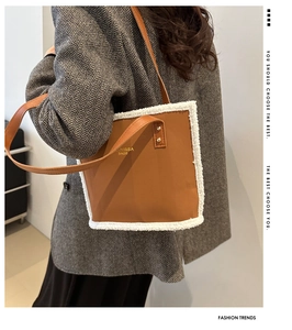 Brown leather tote bag with white faux shearling trim and gold logo detail on shoulder