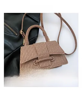 Detailed view of brown hand-woven trapezoid crossbody bag with a curved handle