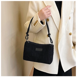 Detail of black corduroy shoulder bag with knotted strap on cream blazer model
