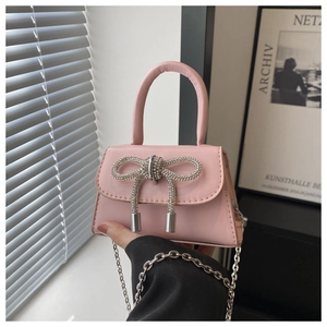 Detail of light pink mini bag with rhinestone bow and silver chain strap for women