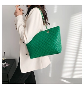 Quilted green leather tote bag with gold chain strap shown on model in soft lighting