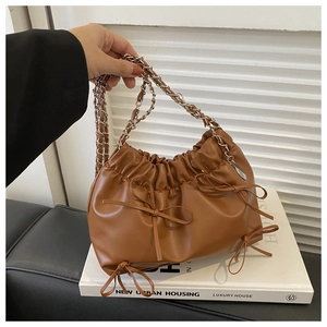 Detail of caramel pleated cloud bag with leather bows and silver chain handle