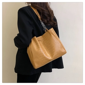 Detail der gelben Krokodilmuster-Tote-Bag mit silberner Kette an der Schulter des Models