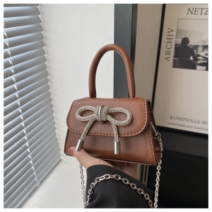 Macro detail of brown patent leather mini bag with sparkling rhinestone bow accent