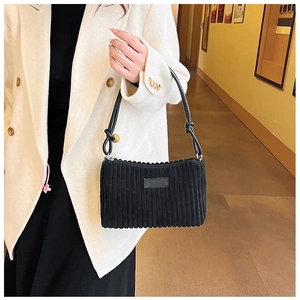 Detail of black corduroy shoulder bag with vertical stripes and leather knot strap