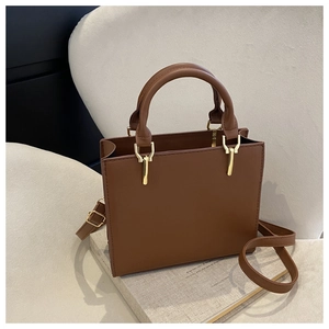Detail of a brown leather handbag with fine stitching and golden metal buckle