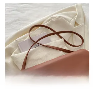 Détail de la bandoulière réglable et de la boucle en métal doré du sac en cuir caramel