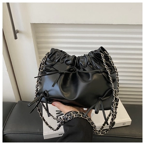 Detail view of the black pleated cloud bag with soft bow decor and chain strap