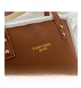 Detail of brown faux shearling trim on a retro leather shoulder bag with gold rivets