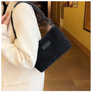 Close-up of black corduroy shoulder bag showing vertical texture and knotted strap detail