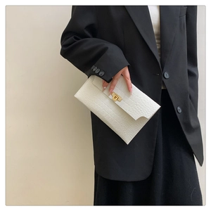 Close-up of a white envelope clutch bag with animal stone texture and gold metal turn-lock