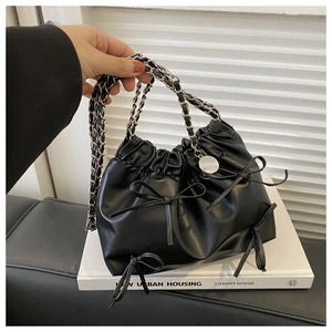 Detail of black leather pleated cloud bag featuring sweet bow accents and chain strap