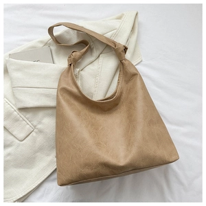Detail of soft khaki faux leather hobo bag with knot shoulder strap on cream blazer