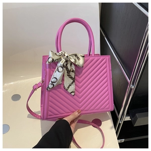 Détail d'un sac à main matelassé rose avec motif chevron et foulard en soie au manche