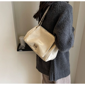 Creamy beige chain bag shown on model highlighting the size and textured finish