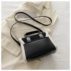 Detail of elegant black leather handbag with white faux fur trim and adjustable shoulder strap