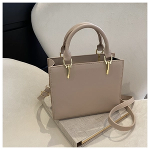 Detailed view of beige leather handbag with gold hardware on a linen textured surface