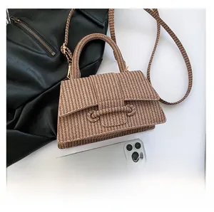 Detail view of a brown woven leather handbag with matching strap and mobile phone for size