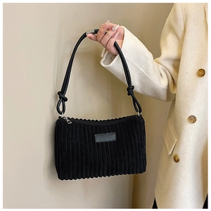 Detailed close-up of a black corduroy handbag featuring a knotted strap and zipper closure