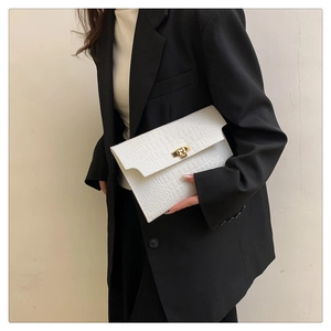 Detail of white envelope clutch bag with embossed crocodile texture and gold metal buckle