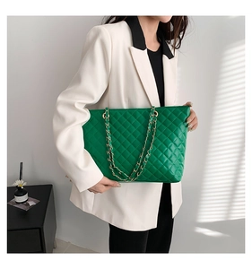 Close-up of bright green quilted leather tote bag with elegant gold chain shoulder strap