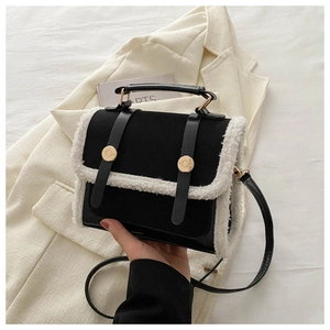 Close-up of black handbag with white faux fur trim and elegant golden buckles