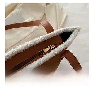 Detail of smooth gold metal zipper on brown faux leather tote with white faux fur trim