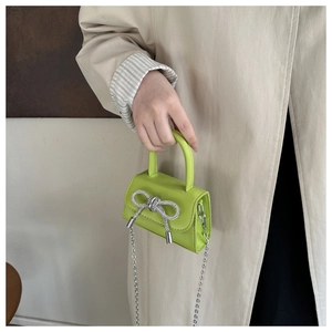 Close-up of a lime green mini bag with sparkling rhinestone bow and silver chain