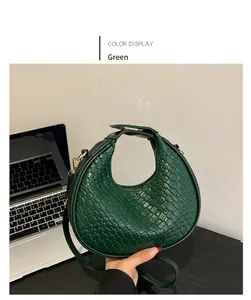 Dettaglio di una borsa hobo in pelle intrecciata verde con hardware dorato e manico