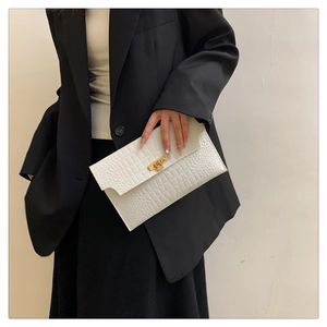 Close-up of a white envelope clutch bag with crocodile texture and gold metal buckle