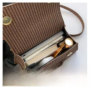 Top view of brown woven PU handbag showing spacious interior with phone and cosmetics