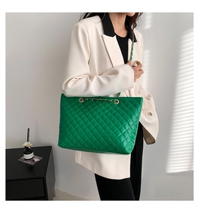 Detail of green quilted tote bag with gold chain handles and diamond stitching pattern