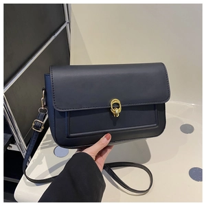 Gros plan d'un sac bandoulière en cuir mat noir avec fermoir rotatif en métal doré