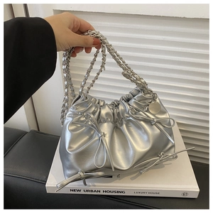 Close-up of silver metallic pleated bucket bag with chain strap and bow details