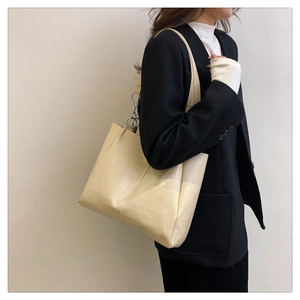 Detailansicht der cremefarbenen Krokodil-Schultertasche mit Silberring an einem Modell