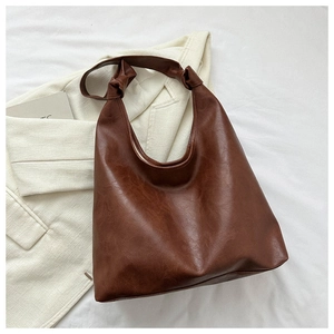 Detail of dark brown PU hobo bag with knotted strap on a minimalist white backdrop