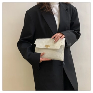 Close-up of a white crocodile texture envelope clutch bag with gold metallic buckle