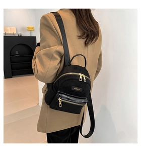 Close-up of black velvet mini backpack featuring a gold FASHION metal plate and zipper