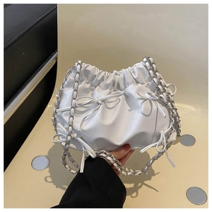 Detailed view of white pleated cloud bag with bow accents and silver chain strap